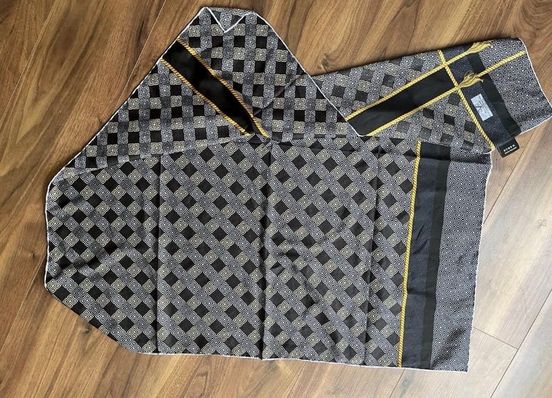Peut inclure: Un foulard et une pochette assortis &agrave; motifs noirs et gris. Le foulard et la pochette pr&eacute;sentent un motif de losanges r&eacute;p&eacute;t&eacute;s avec des accents noirs et dor&eacute;s. Le foulard a une bande noire et dor&eacute;e au centre et une bordure blanche.