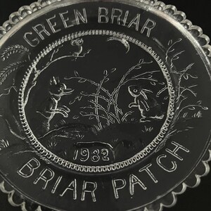 May include: A clear glass plate with a scalloped edge featuring an embossed design of a fox and a rabbit in a briar patch. The text "GREEN BRIAR" is at the top, "BRIAR PATCH" is at the bottom, and the year "1982" is centered at the base.