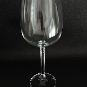 May include: A clear glass wine glass with a tall stem and a wide bowl. The glass is empty and appears to be new.