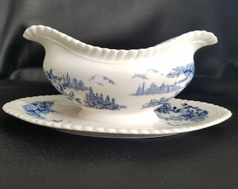 May include: A white porcelain gravy boat with a blue and white floral pattern. The boat has a scalloped edge and a matching saucer.