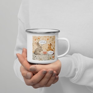 May include: White enamel mug featuring a watercolor illustration of two rabbits conversing. One rabbit asks "What's on your mind?" while the other replies "Tiny Mulitfication". The mug has a silver rim and a white handle.