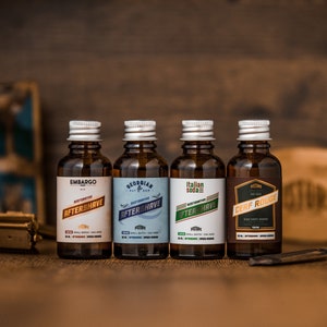 May include: Four amber glass bottles with silver caps and labels. The bottles contain aftershave and are labelled with different names and scents: Embargo, Georgian Bay Rum, Italian Soda, and Cerf Rouge.