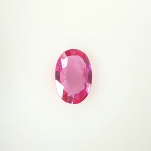 May include: A pink oval-shaped gemstone with facets.
