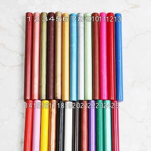 Peut inclure: Vingt-cinq bâtonnets de cire assortis pour sceller des enveloppes ou pour des travaux manuels. Les bâtonnets sont disposés en deux rangées, numérotées de 1 à 25. Les couleurs comprennent le rouge, le rose, le jaune, l'or, l'argent, le bleu, le vert, le marron, le noir et le blanc.