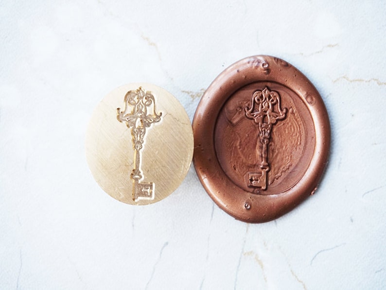 Peut inclure: Un tampon de cire en forme de cl&eacute; et une empreinte de cire de couleur bronze. Le tampon est un m&eacute;tal circulaire de couleur laiton avec un motif de cl&eacute; orn&eacute;. L'empreinte est une image en relief d&eacute;taill&eacute;e de la cl&eacute; dans une cire circulaire de couleur bronze.