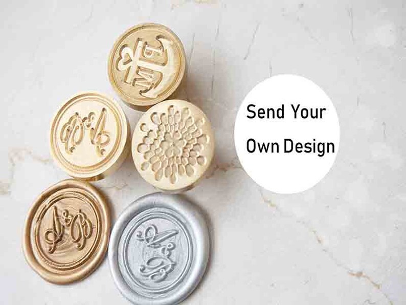 Peut inclure: Plusieurs tampons de cire personnalis&eacute;s avec des motifs et des couleurs vari&eacute;s. Les tampons comprennent une ancre, des initiales et un motif floral. Un sceau est argent&eacute;, les autres sont dor&eacute;s ou bronze. Le texte "Send Your Own Design" est inclus.