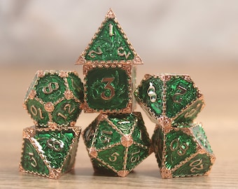 May include: A set of seven green and gold metal dice with intricate designs. The dice are arranged in a pyramid shape, with the highest die showing a number one.
