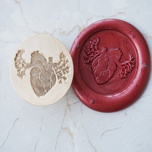 May include: A wooden stamp with a detailed anatomical heart design, and a red wax seal with the same design.