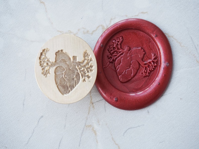 May include: A wooden stamp with a detailed anatomical heart design, and a red wax seal with the same design.