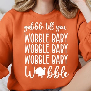 May include: Orange sweatshirt with the text "gobble til you wobble baby wobble baby wobble baby wobble" and a white turkey graphic.