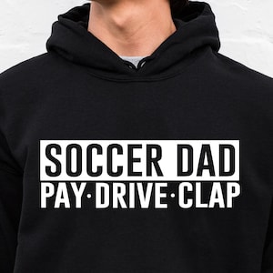 Op de afbeelding: Zwart hoodie met witte tekst die "Soccer Dad Pay-Drive-Clap" zegt.