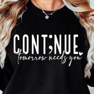 May include: Black sweatshirt with white text that reads "CONTINUE; tomorrow needs you" with a small heart symbol.