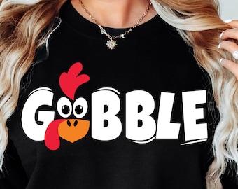 Może przedstawiać: Czarny sweter z białym nadrukiem indyka z napisem "GOBBLE".