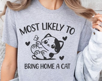 May include: Gray t-shirt with a black and white cartoon cat and the text "Most Likely To Bring Home A Cat".