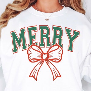 May include: White sweatshirt with a green and red "Merry" graphic featuring a red bow.