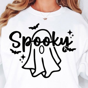 Op de afbeelding: Wit sweatshirt met een zwarte geest en de tekst "Spooky" bedrukt op de voorkant.