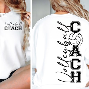 K&ouml;nnte beinhalten: Wei&szlig;er Pullover mit schwarzem Text, der auf der Vorderseite "Volleyball COACH" und auf der R&uuml;ckseite "COACH" mit einem Volleyball und einem Herzmotiv lautet.