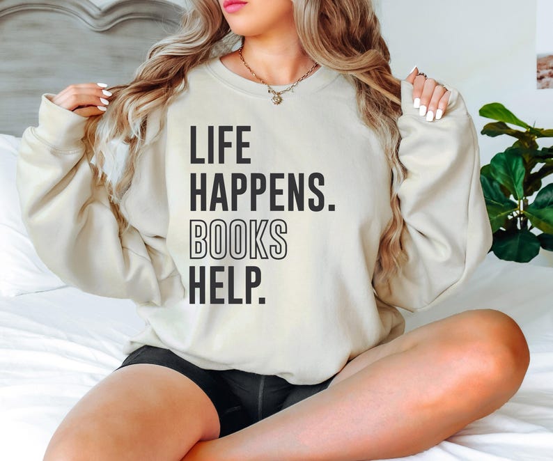 May include: A cream-colored sweatshirt with the text "LIFE HAPPENS. BOOKS HELP." printed in black.