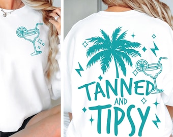 May include: White sweatshirt with a teal palm tree and the text "Tanned and Tipsy" on the back. The front of the sweatshirt has a teal cocktail glass with a lime wedge and a straw.
