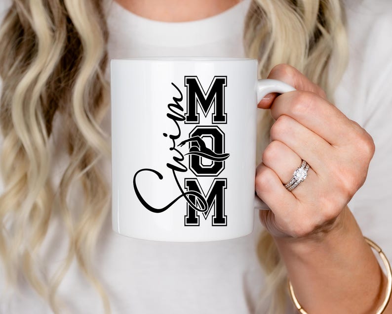 May include: White ceramic mug with a black design that says "Swim Mom" in a stylized font.