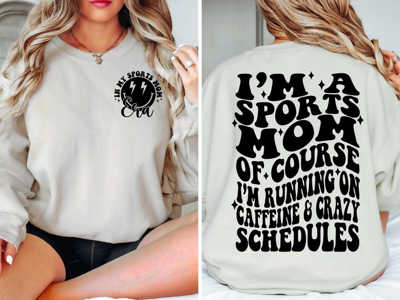 Pode incluir: Uma camisa de moletom branca com texto preto que diz "Eu sou uma m&atilde;e esportiva, claro que estou correndo com cafe&iacute;na e hor&aacute;rios loucos". A frente da camisa de moletom tem um rosto sorridente preto com raios e o texto "Na minha era de m&atilde;e esportiva".
