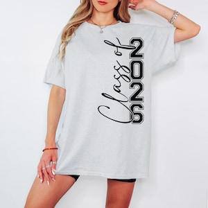 May include: Light gray t-shirt with the text "Class of 2026" in black script and block letters. The shirt is a casual style, suitable for graduation or a class reunion.