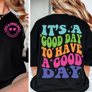 May include: Black t-shirt with a rainbow coloured graphic that says "It's a good day to have a good day".