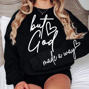 May include: Black sweatshirt with white text that reads "but God made a way" with a heart symbol replacing the "o" in God.