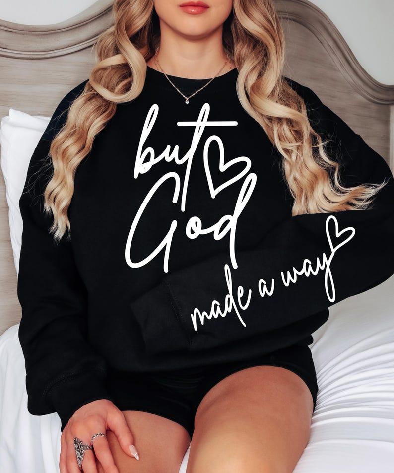 May include: Black sweatshirt with white text that reads "but God made a way" with a heart symbol replacing the "o" in God.