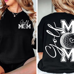 Może przedstawiać: Czarny T-shirt z białym nadrukiem graficznym, na kt&oacute;rym widnieje napis "Golf Mom" z piłką golfową i sercem. Z tyłu T-shirt znajduje się większa piłka golfowa i serce z napisem "Golf" napisanym kursywą i "MOM" dużymi literami.