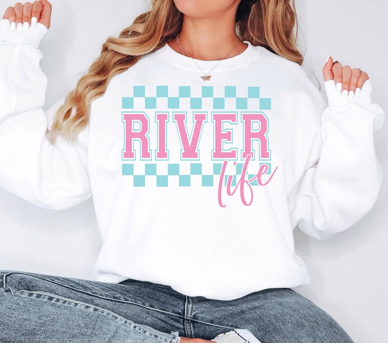 May include: White sweatshirt with a blue and white checkered pattern and the text "RIVER life" in pink.