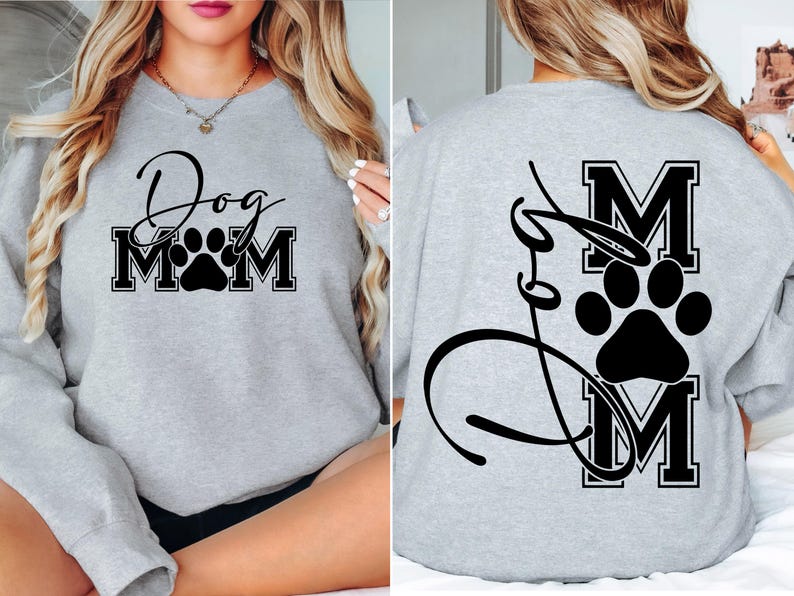 Puede incluir: Sudadera gris con texto negro que dice "Dog Mom" con una huella de pata en el medio de la palabra "Mom". La parte posterior de la sudadera tiene un dise&ntilde;o negro con la palabra "Mom" en una fuente grande con una huella de pata en el medio.