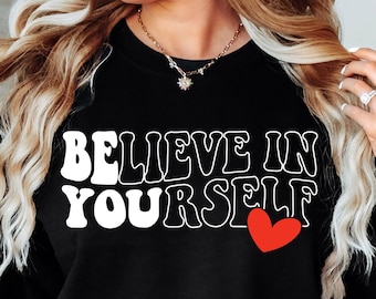 May include: Black sweatshirt with white text that reads "BELIEVE IN YOURSELF" with a red heart.