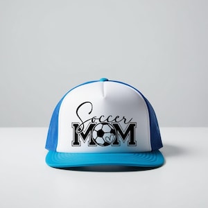 May include: A white and blue trucker hat with a black and white graphic that says "Soccer Mom" with a soccer ball in the middle of the word "Mom".