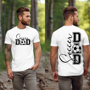 Peut inclure: T-shirt blanc avec un texte noir qui dit "Soccer Dad" et un graphique de ballon de football. Le dos du t-shirt a le texte "Soccer Dad" verticalement avec le graphique de ballon de football au milieu.