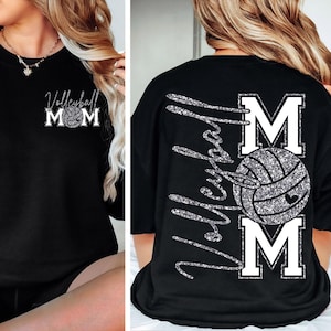 May include: Black sweatshirt with the text "Volleyball Mom" in a silver glitter design. The front features the text "Volleyball Mom" with a volleyball graphic. The back has "Volleyball" vertically and "MOM" with a volleyball graphic.