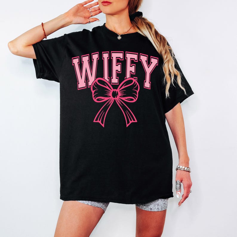 May include: Black oversized t-shirt with the text "WIFFY" in pink letters and a pink bow.