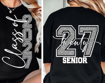 Könnte beinhalten: Ein schwarzes T-Shirt mit weißen und silbernen Glitzergrafiken. Die Vorderseite zeigt den Text Class of 2027. Die Rückseite zeigt die Zahl 27 in silbernem Glitzer mit weißem Rand, das Wort twenty in Schreibschrift und SENIOR darunter.
