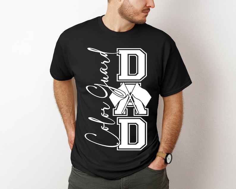 May include: Black t-shirt with white text that reads "Color Guard Dad" with a stylized graphic of a flag and drums.