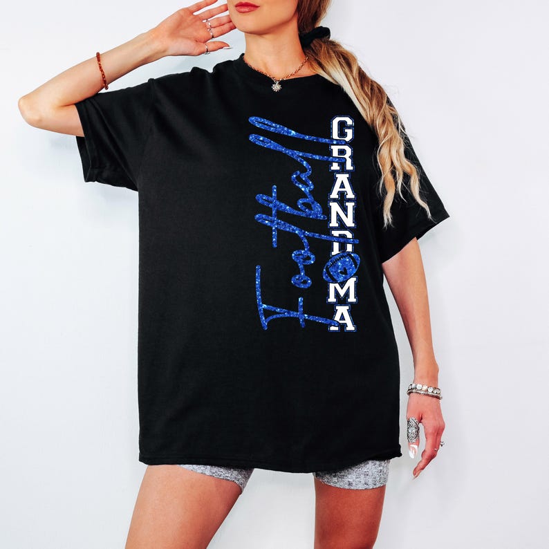 Pu&ograve; includere: T-shirt nera con la scritta "Football Grandma" in glitter blu. La parola "Grandma" &egrave; in lettere bianche. La maglietta presenta una grafica di football americano.
