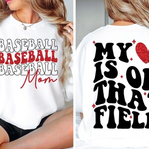 Pu&ograve; includere: Felpa bianca con testo in glitter rosso che dice "Baseball Baseball Baseball Mom" sul davanti e "My heart is on that field" con un cuore in glitter rosso sul retro.