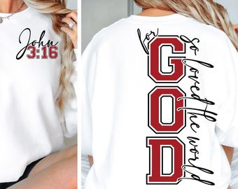 Op de afbeelding: Wit sweatshirt met de tekst "John 3:16" op de voorkant en "For God so loved the world" met het woord "GOD" in grote rode letters op de achterkant.