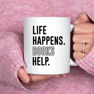 May include: White ceramic mug with black text that reads "Life Happens. Books Help."