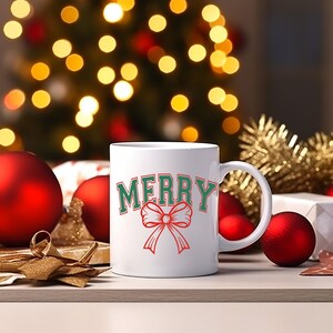 May include: White ceramic mug with a green and red "Merry" design and a red bow.