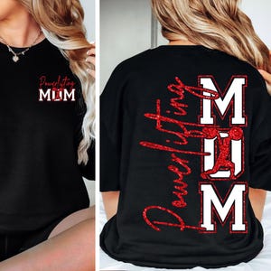 Puede incluir: Sudadera negra con la inscripción "Powerlifting MUM" en purpurina roja. La parte delantera de la camiseta tiene "Powerlifting MUM" en letras de purpurina roja. La parte trasera de la camiseta tiene "Powerlifting" en purpurina roja y la palabra "MUM" en letras blancas.