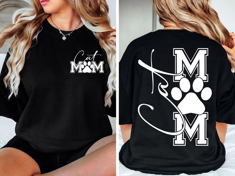 May include: Black sweatshirt with the text "Cat Mom" in white script and block letters, featuring a paw print. The back of the shirt has a large paw print and the letters "MOM".