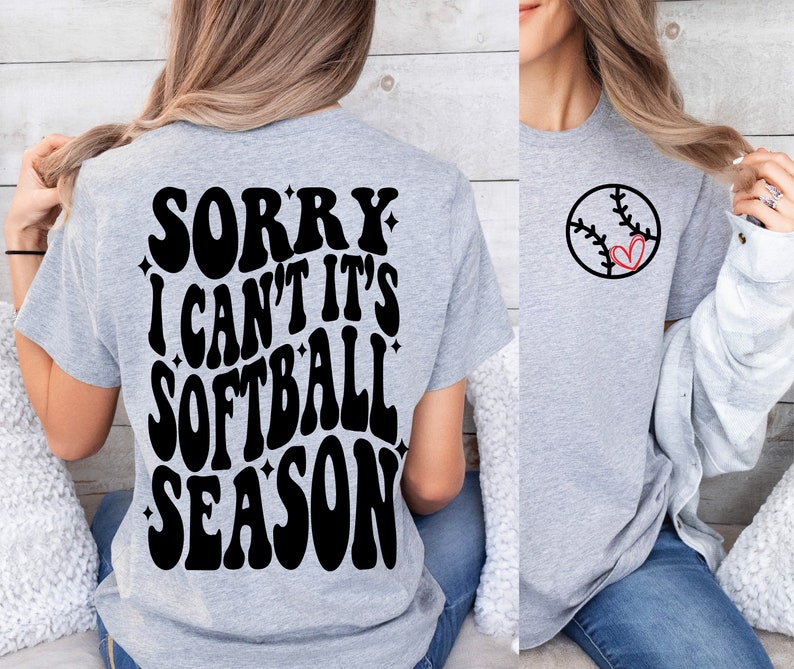 May include: A gray t-shirt with the text "Sorry I can't it's softball season" in black on the back. The front of the shirt has a black and red softball with a heart in the middle.