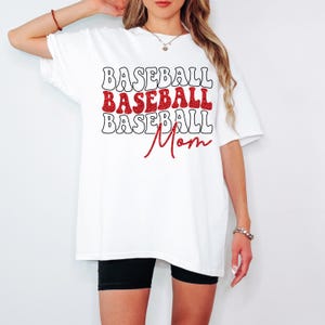 Pu&ograve; includere: Maglietta bianca oversize con testo rosso glitterato che recita "Baseball Baseball Baseball Mom".