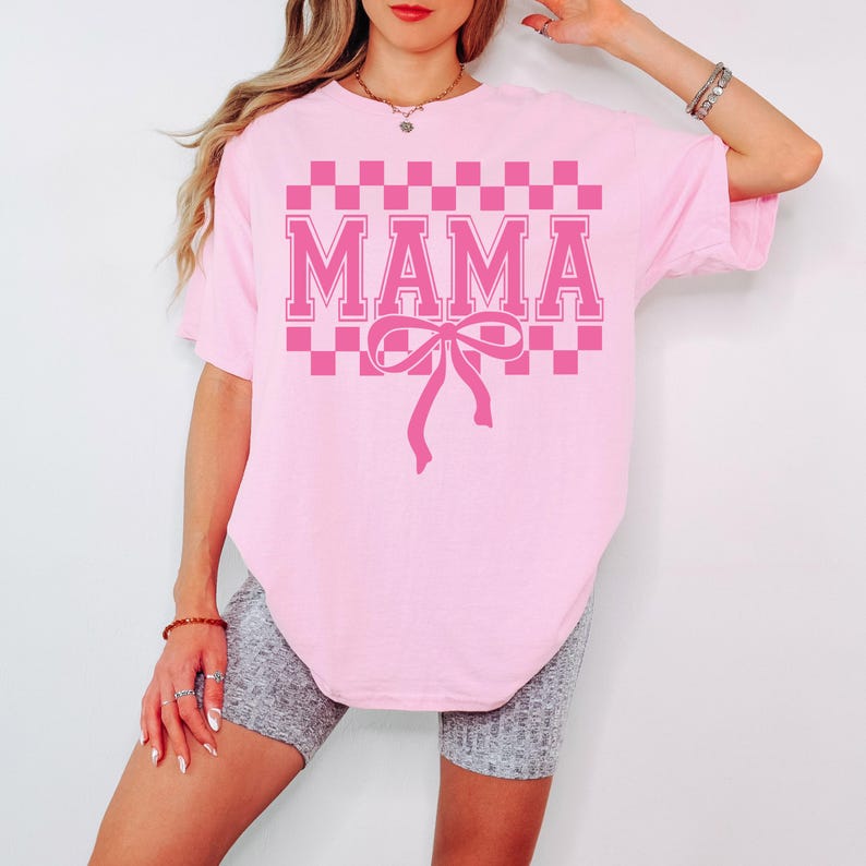 May include: Pink t-shirt with a checkered pattern and the word "MAMA" in pink letters with a pink bow underneath.