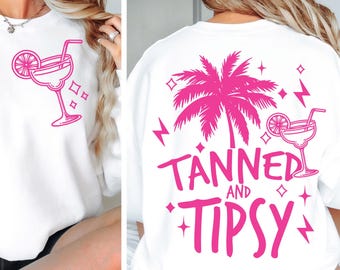May include: White sweatshirt with pink text that says "Tanned and Tipsy" with a palm tree and a cocktail glass graphic.